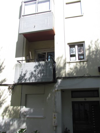 A varanda da sede, com vassouras e panos pendurados, no 1 andar, lado esquerdo.